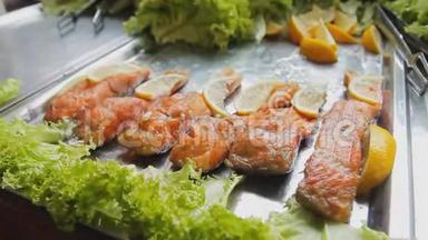 烤红鲑鱼加沙拉。 桌上放着青菜和柠檬的煮熟的鱼片。 <strong>美食节</strong>上烤鱼